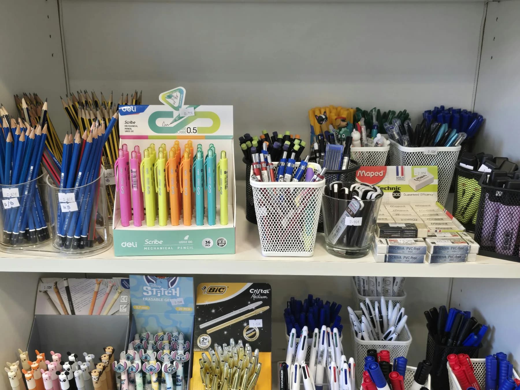 Lápis de grafite, lapiseiras coloridas, borrachas e porta-canetas com esferográficas numa prateleira
