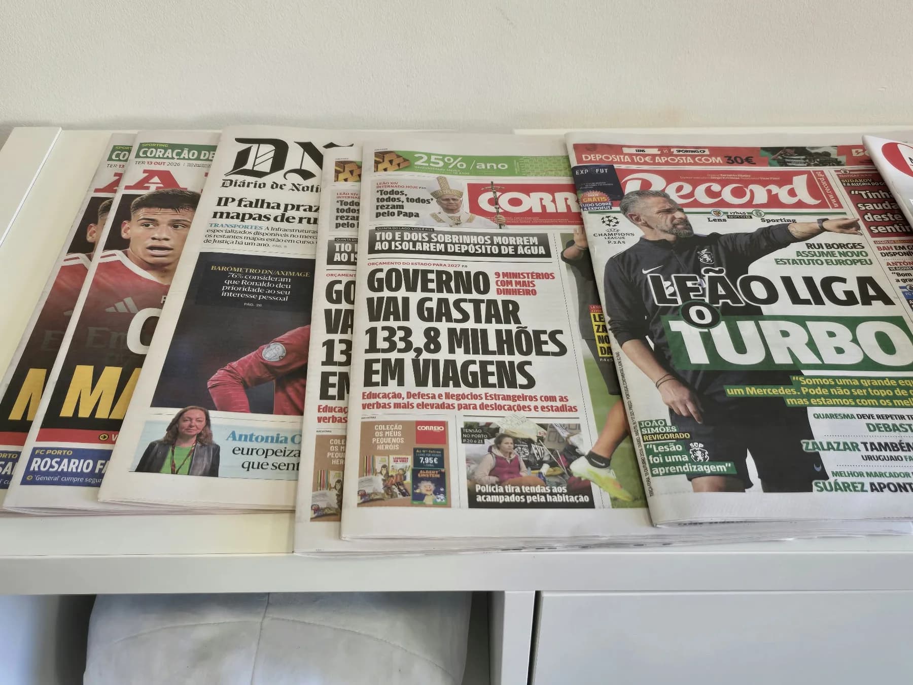 Jornais diários e desportivos dispostos lado a lado num balcão branco